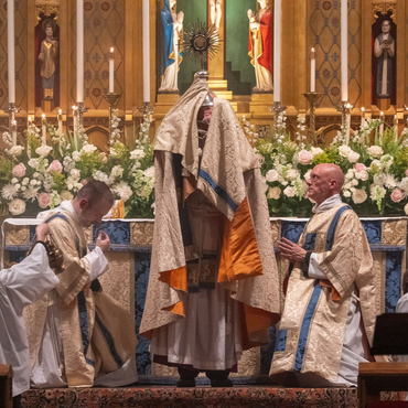A religious procession with altar servers carrying candles and incense at an altar, in church.