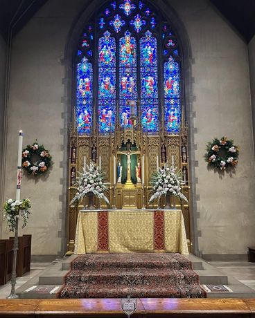 A religious procession with altar servers carrying candles and incense at an altar, in church.