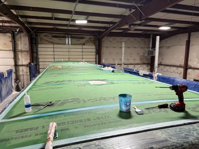 Interior shot of a large workshop with a green-covered surface and tools laid out.