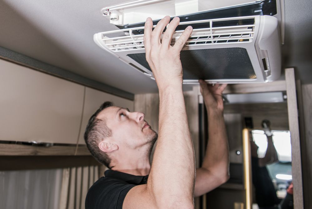 Man installing an air conditioner in a camper van.