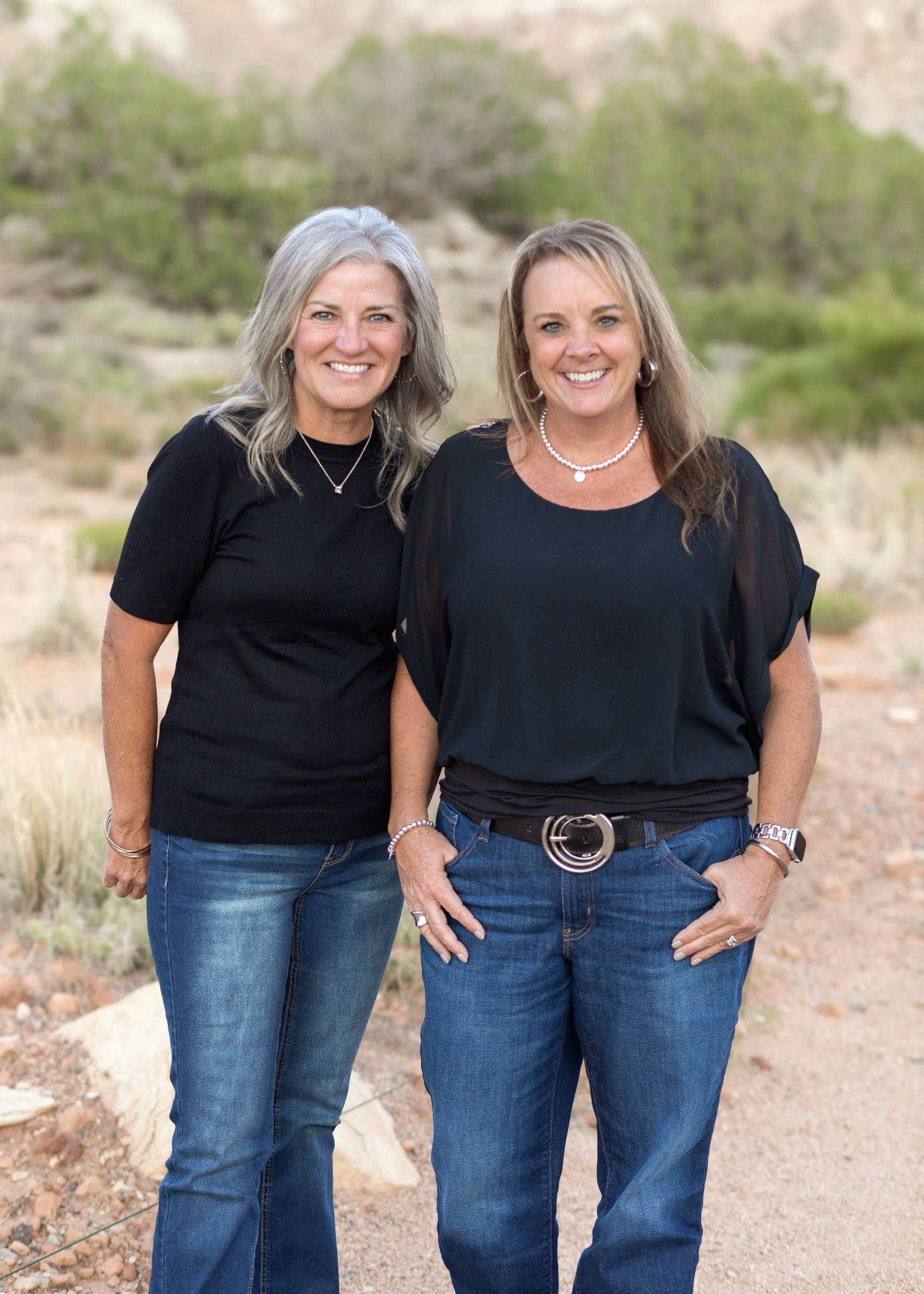 Two women are posing for a picture together in the desert.