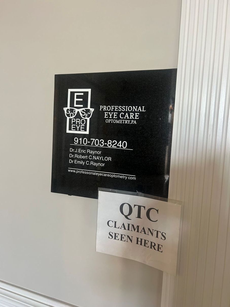 Black wall sign beside a small paper notice reading “QTC students seen here” in Eastover, NC.