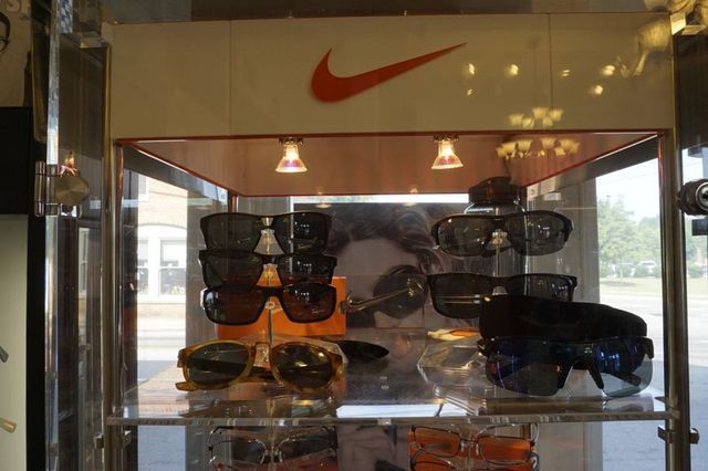 A glass display case featuring various Nike sunglasses under bright overhead lights.
