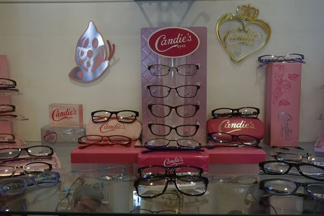 A retail display of Candie's brand eyeglasses, featuring multiple pairs on a central stand, shelves, and cases.
