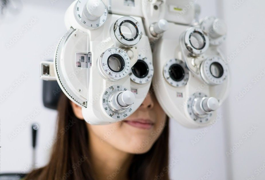 A person having their vision tested with an ophthalmic phoropter in an eye doctor's office.