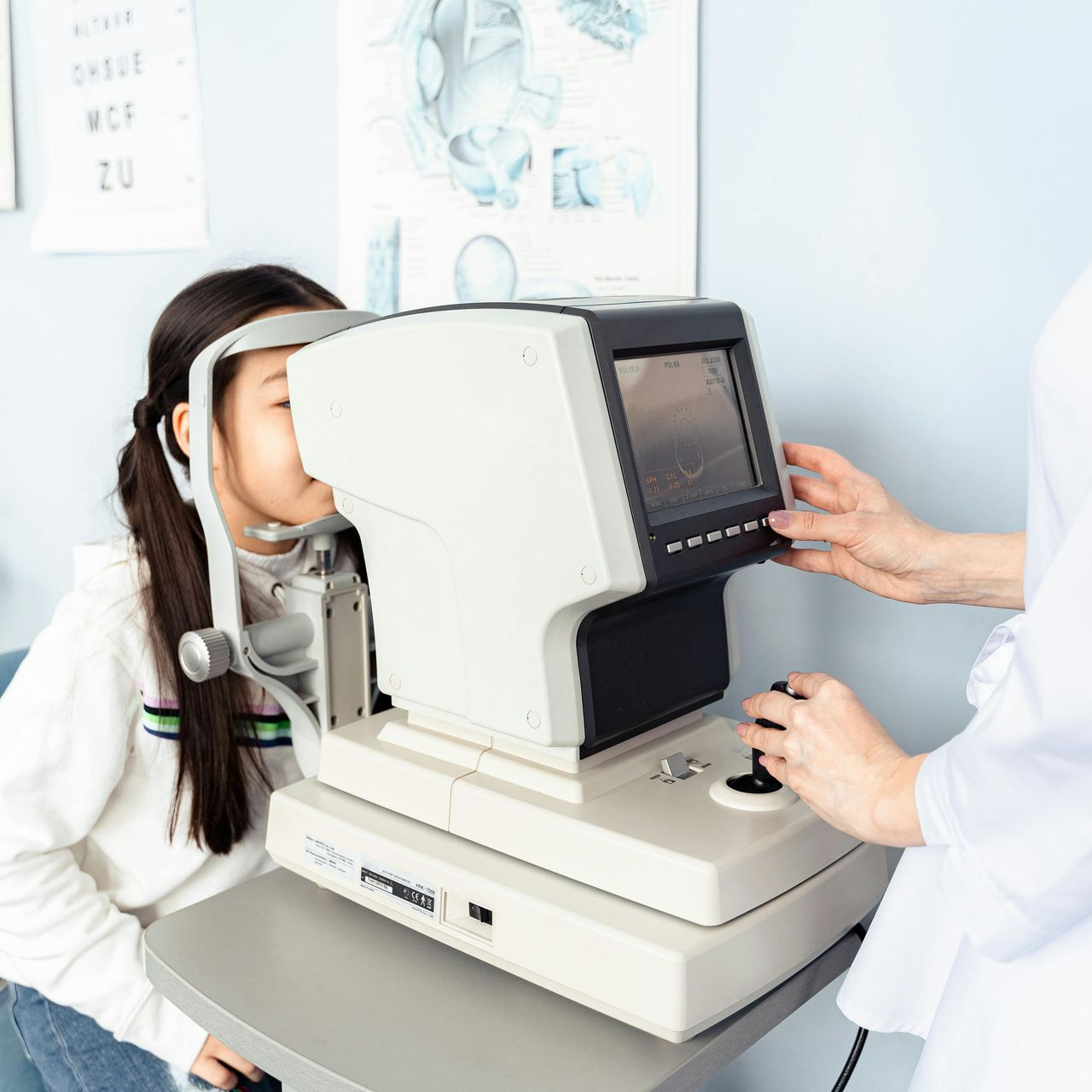 An eye doctor using an autorefractor to examine a patient's vision in a clinic.
