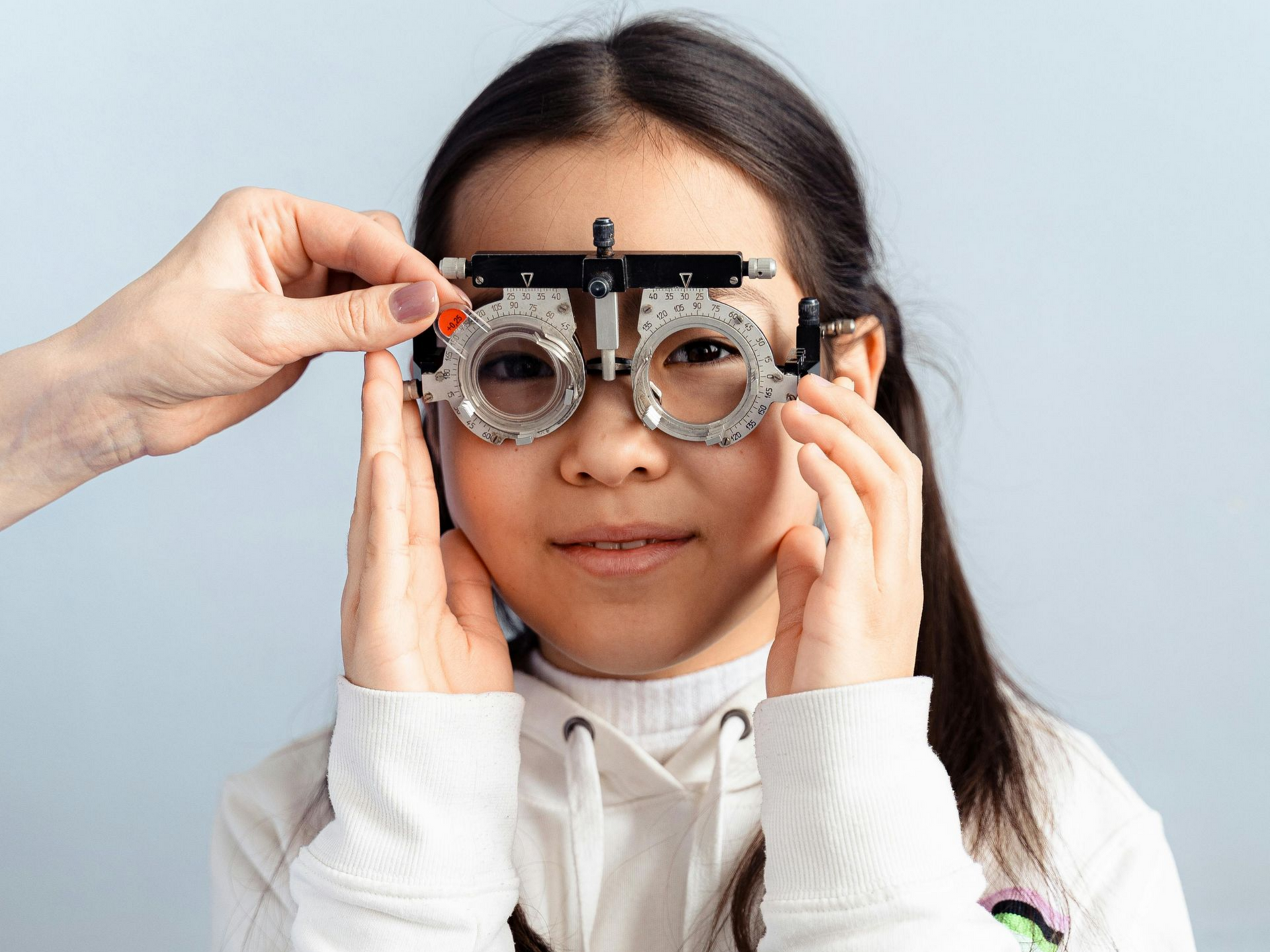 A person holds a trial frame over a child’s eyes during a vision examination.