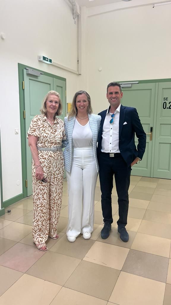 A man and two women are standing next to each other in a hallway.