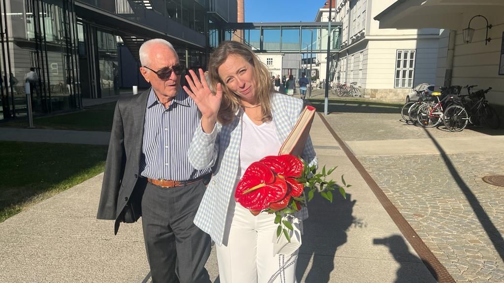 A man and a woman are standing next to each other holding flowers.