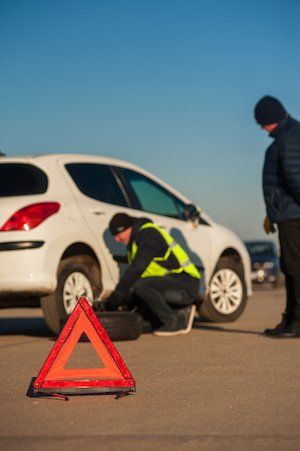 A man is changing a tire on a white car.