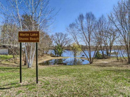 A sign for martin lake shores beach is sitting in the middle of a grassy field.