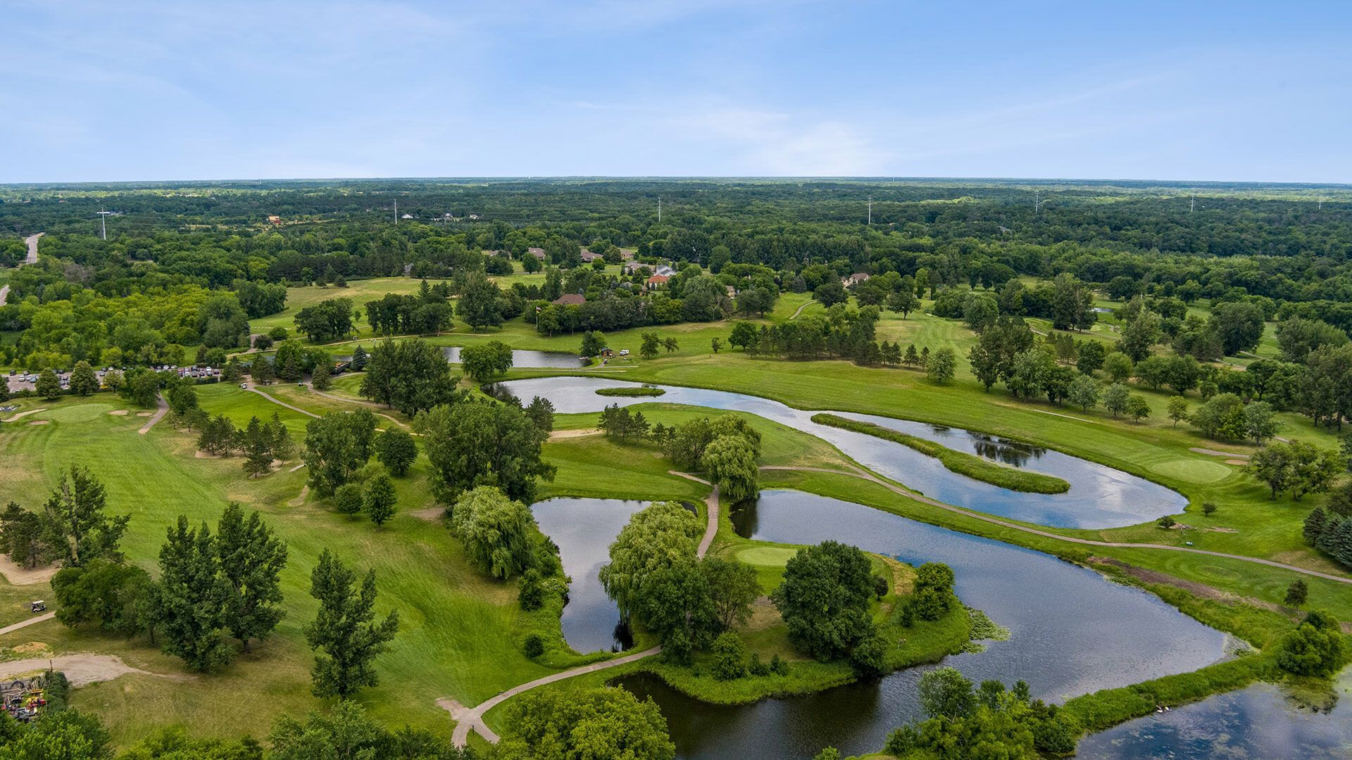 An aerial view of a golf course surrounded by trees and water.