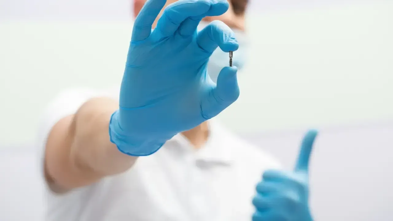 Zierlich, schonend und doch stabil: Minimalinvasives Implantat Minimalinvasives Implantat zwischen zwei Fingern