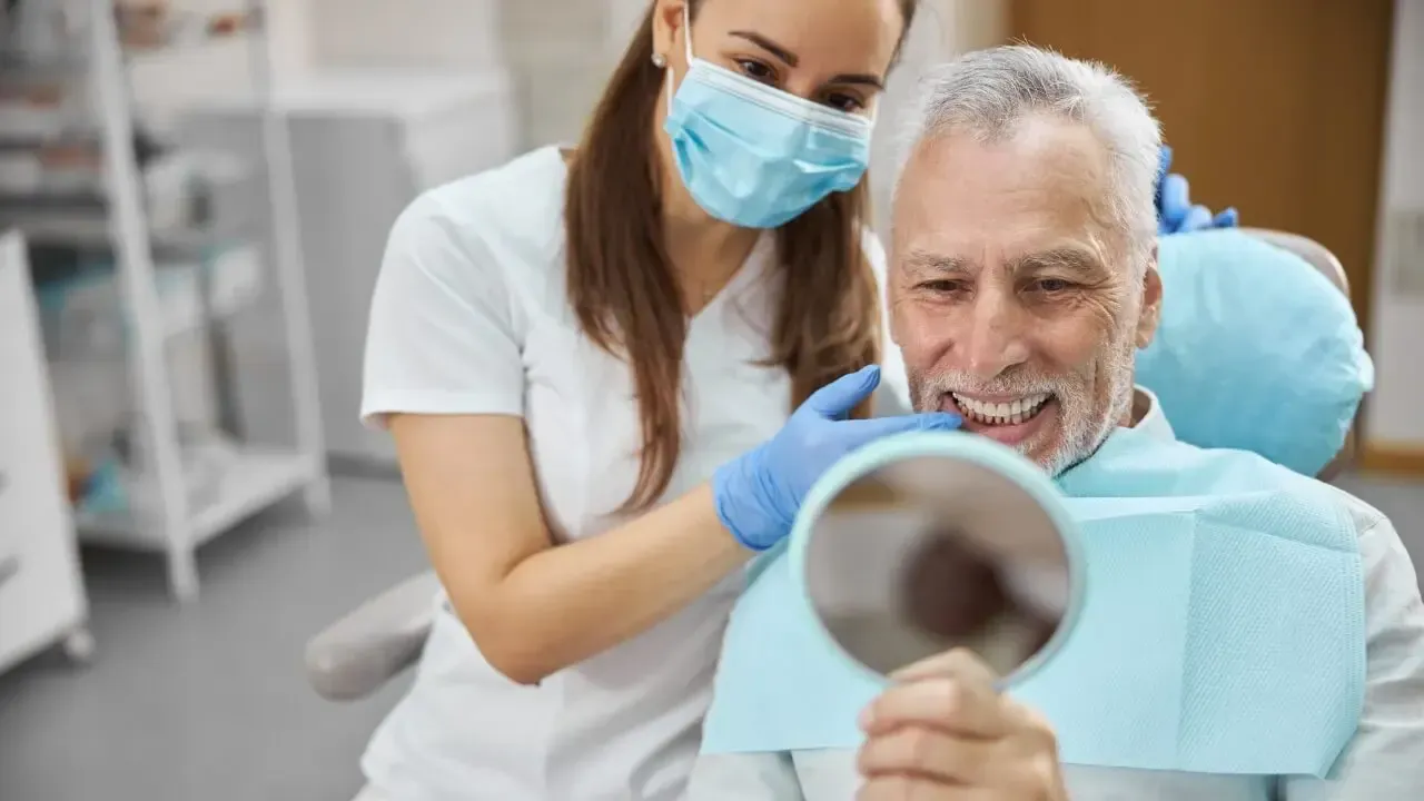 Der erste Blick in den Spiegel: nach der Implantation. Patient bekommt seine neuen Zähne im Spiegel gezeigt.