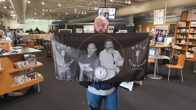 Person in a store holding a large black banner with a black-and-white portrait and clock design