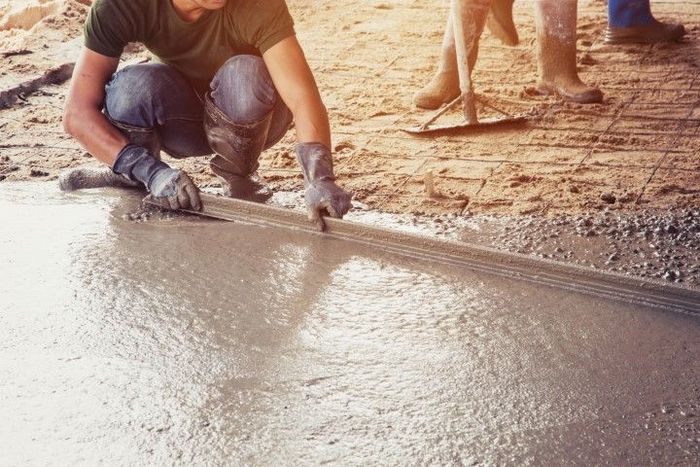 Worker smoothing wet concrete on a construction site.