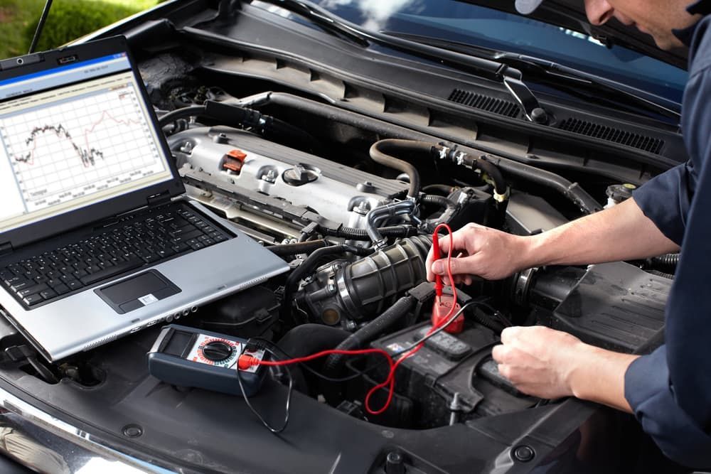 A Man is Working on the Engine of a Car With a Laptop β Jim Wall Automotive in Mittagong, NSW