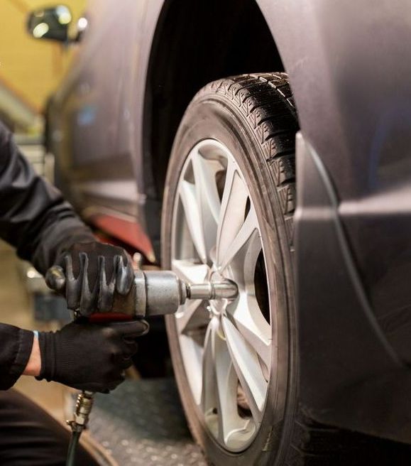 A Person is Changing a Tyre on a Car — Jim Wall Automotive in Mittagong, NSW