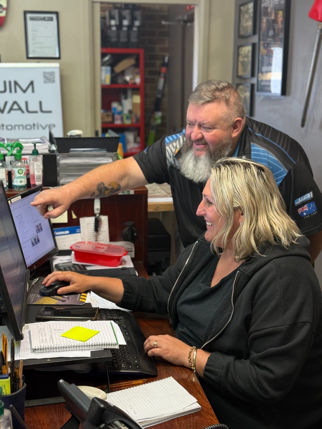A Man and a Woman Are Sitting at a Desk Looking at a Computer Screen — Jim Wall Automotive in Mittagong, NSW