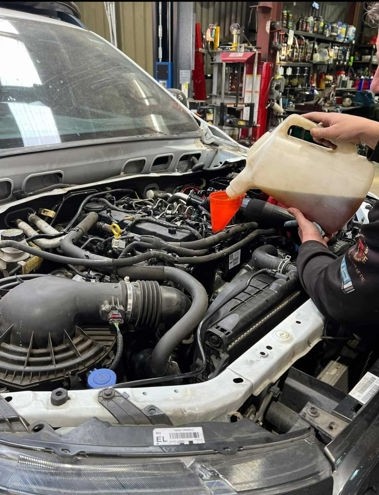 A Person is Inspecting the Car and Pouring Oil Into the Engine of a Car — Jim Wall Automotive in Mittagong, NSW