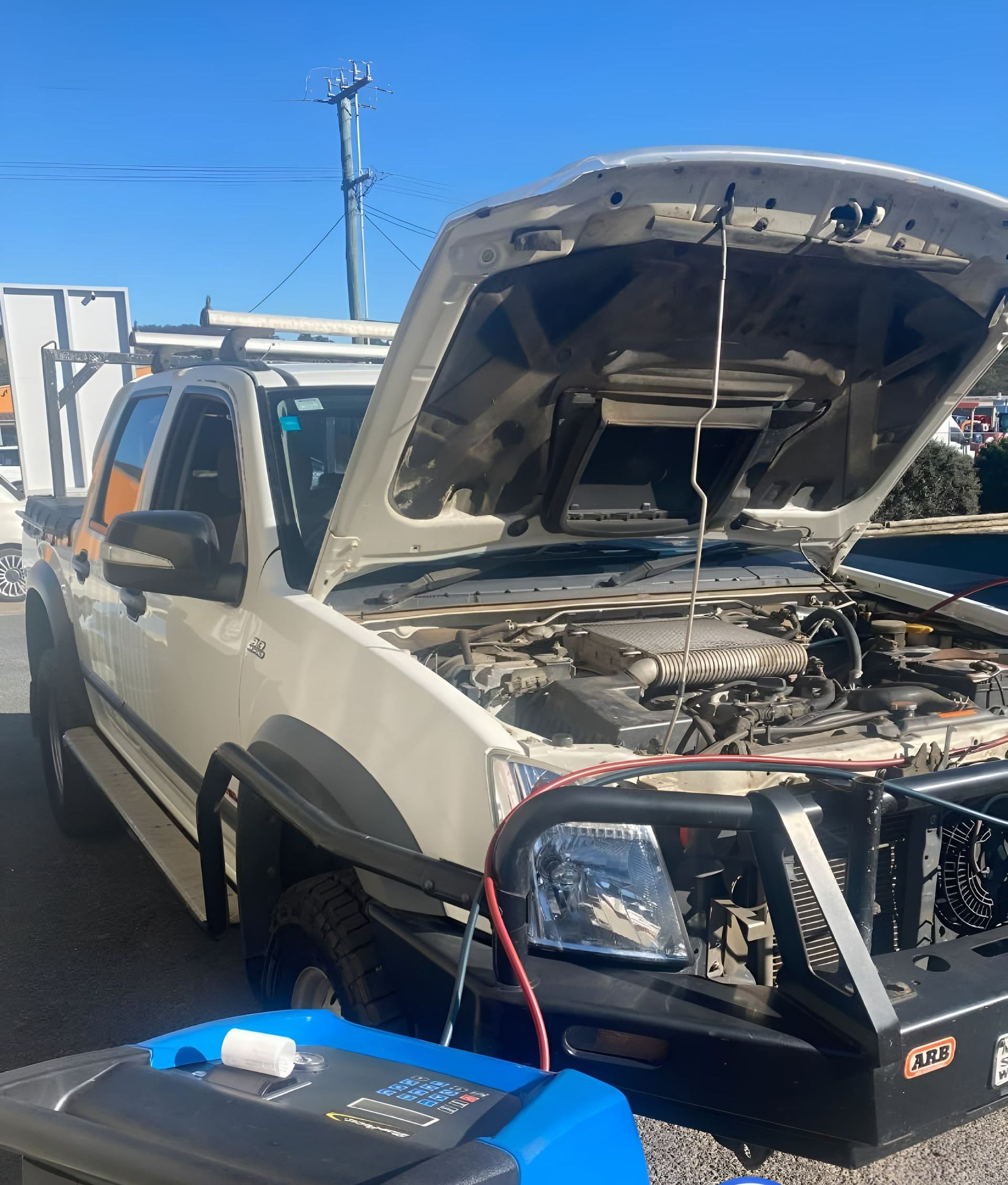 A Man is Working on a Car Battery With a Multimeter — Jim Wall Automotive in Mittagong, NSW