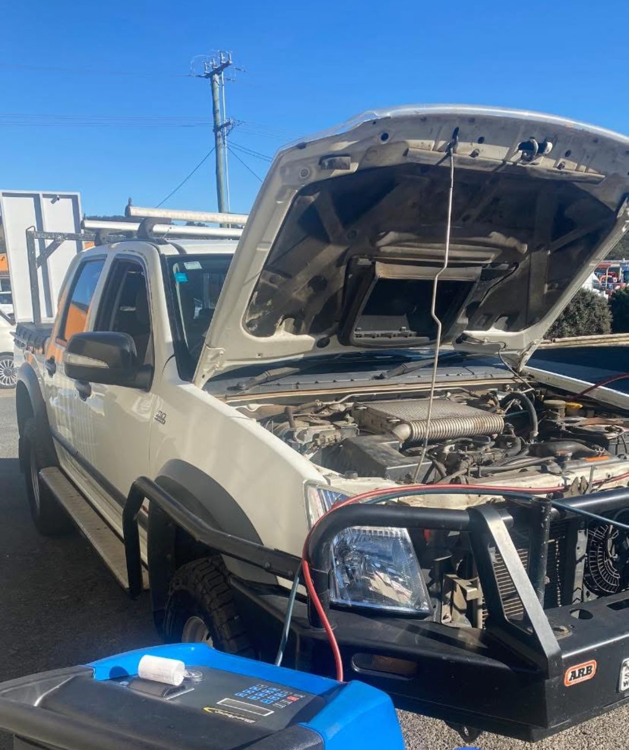 A White Truck With the Hood Open is Being Charged by a Generator — Jim Wall Automotive in Mittagong, NSW