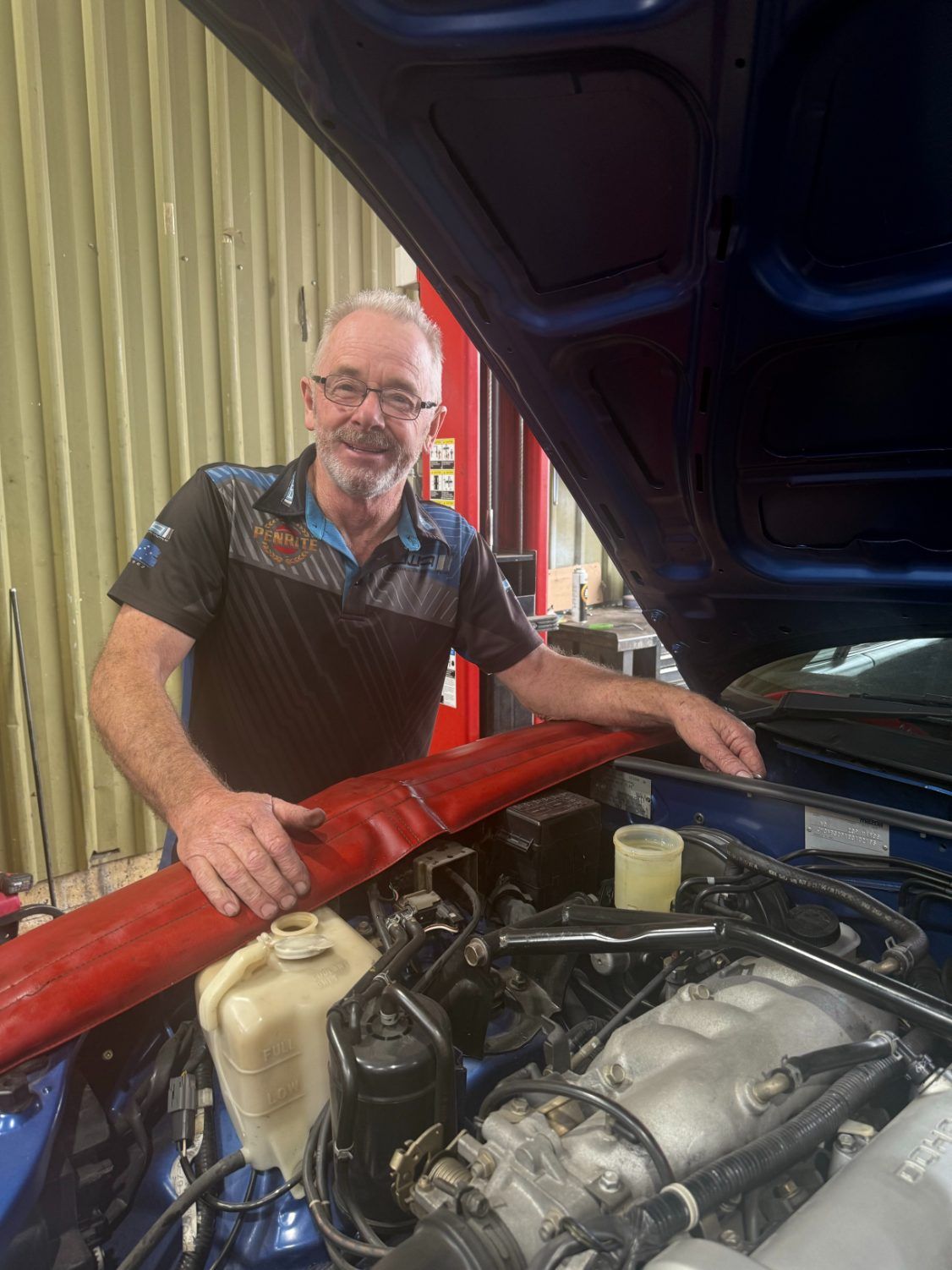 A Man is Standing Under the Hood of a Car — Jim Wall Automotive in Mittagong, NSW