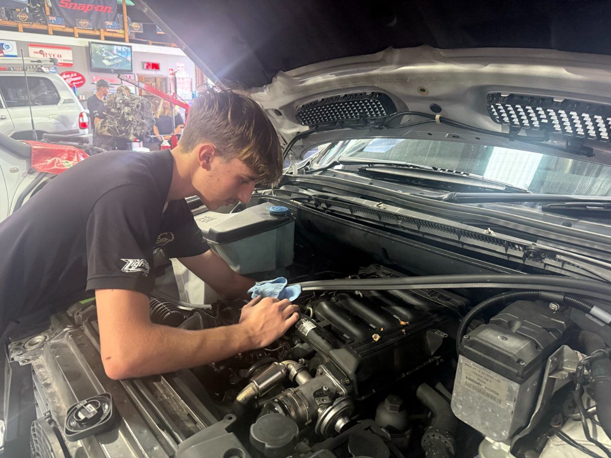 A Young Man is Working on the Engine of a Car — Jim Wall Automotive in Mittagong, NSW