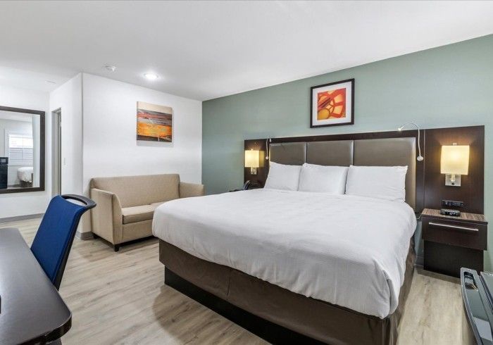Bedroom with a large wooden headboard, two bedside tables with lamps, a vanity, and framed art.