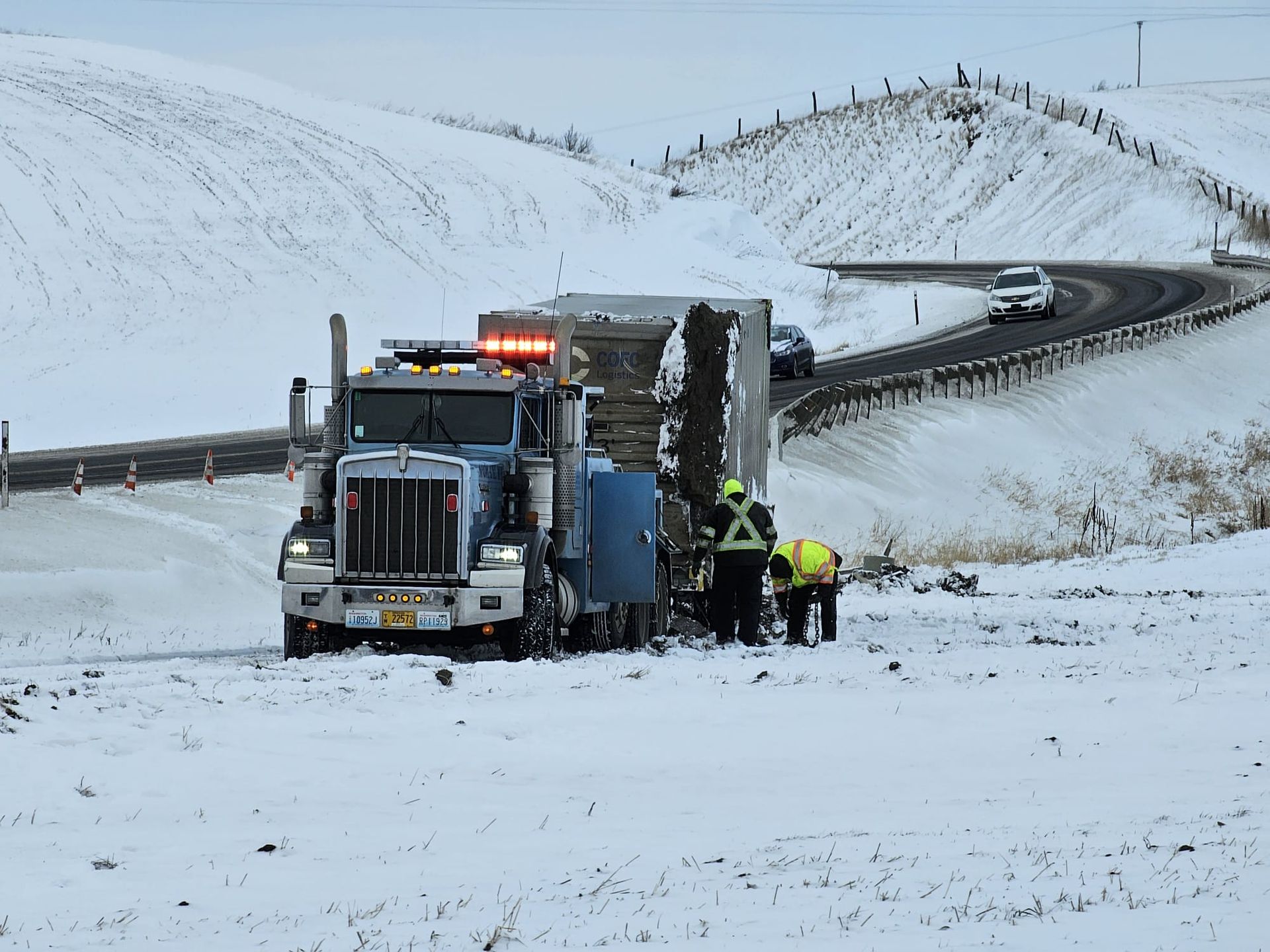 A semi truck is driving down a snowy road