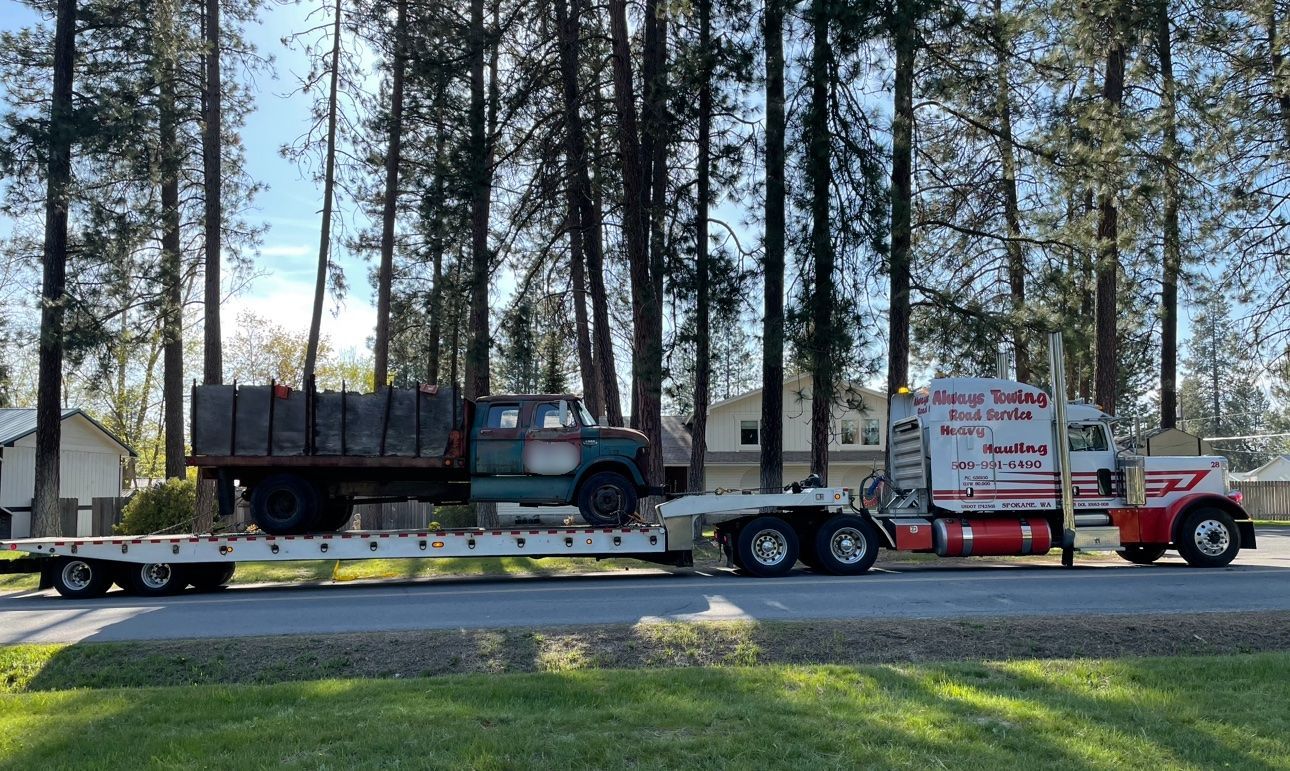 A semi truck is carrying a truck on a flatbed trailer.