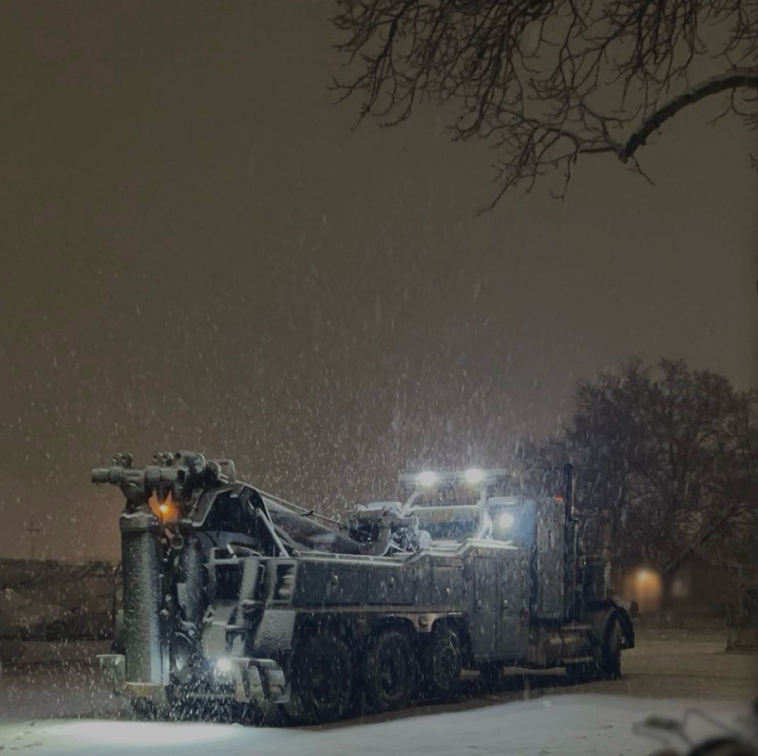 A truck is parked in the snow at night.