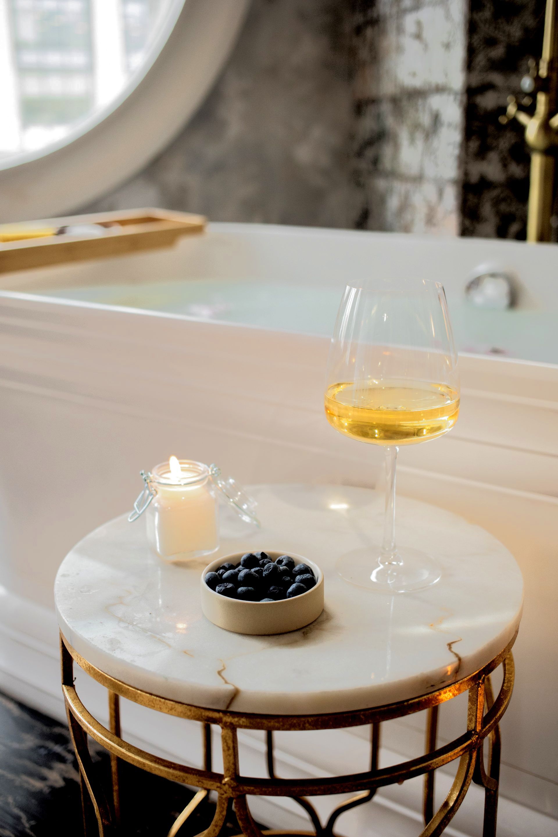 Relaxing bath with wine and berries in a clean bathroom