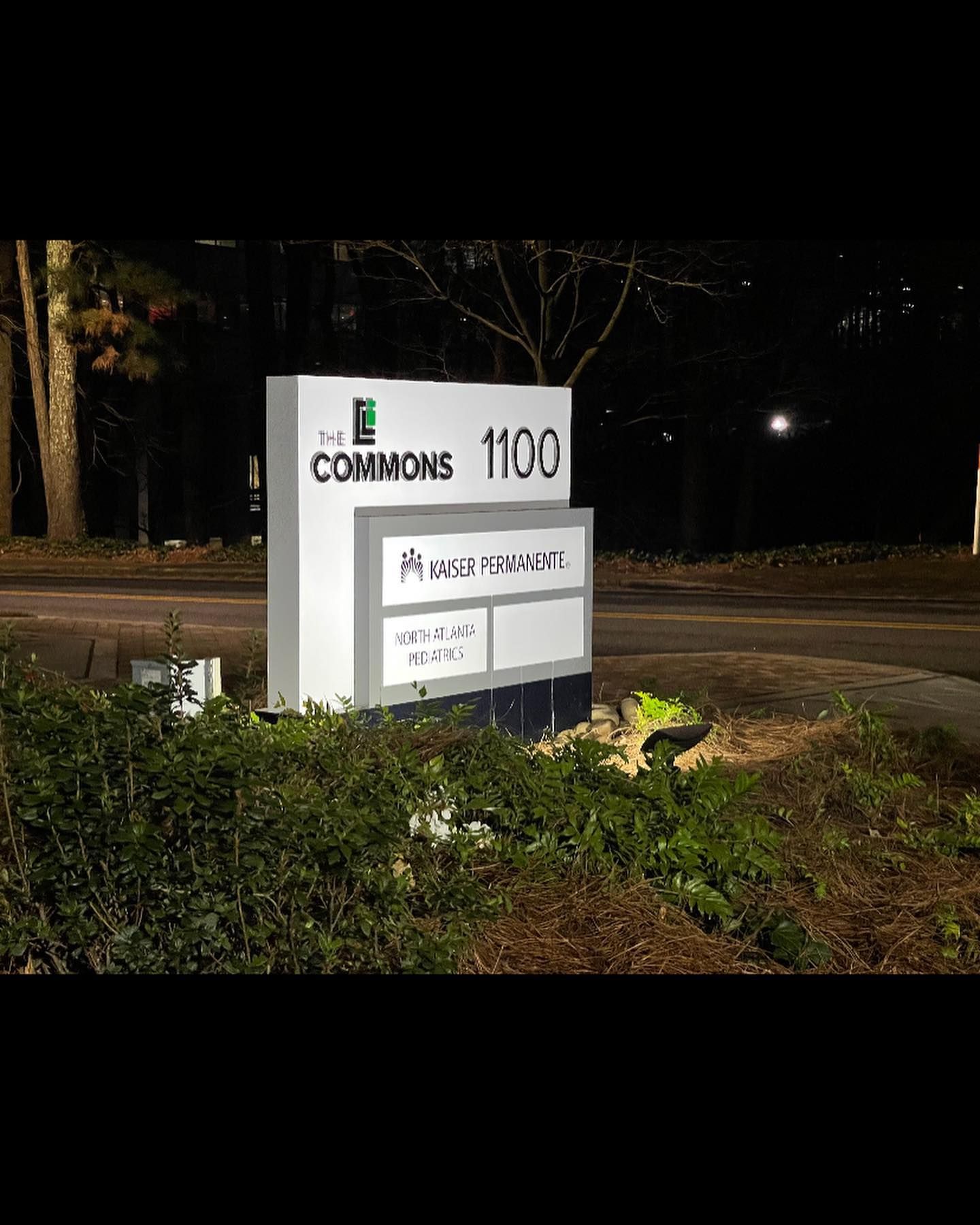 Sign for The Commons, address 1100, at night; includes business name 