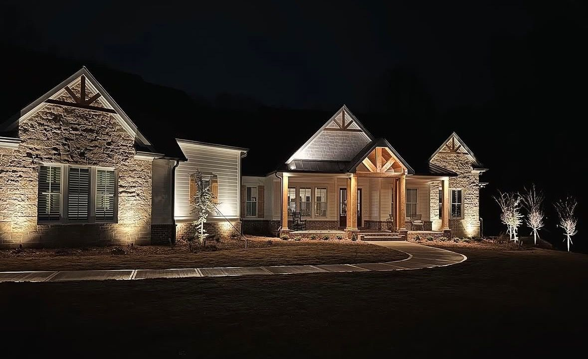 Stone house at night, warmly lit exterior with multiple gables against a dark sky.
