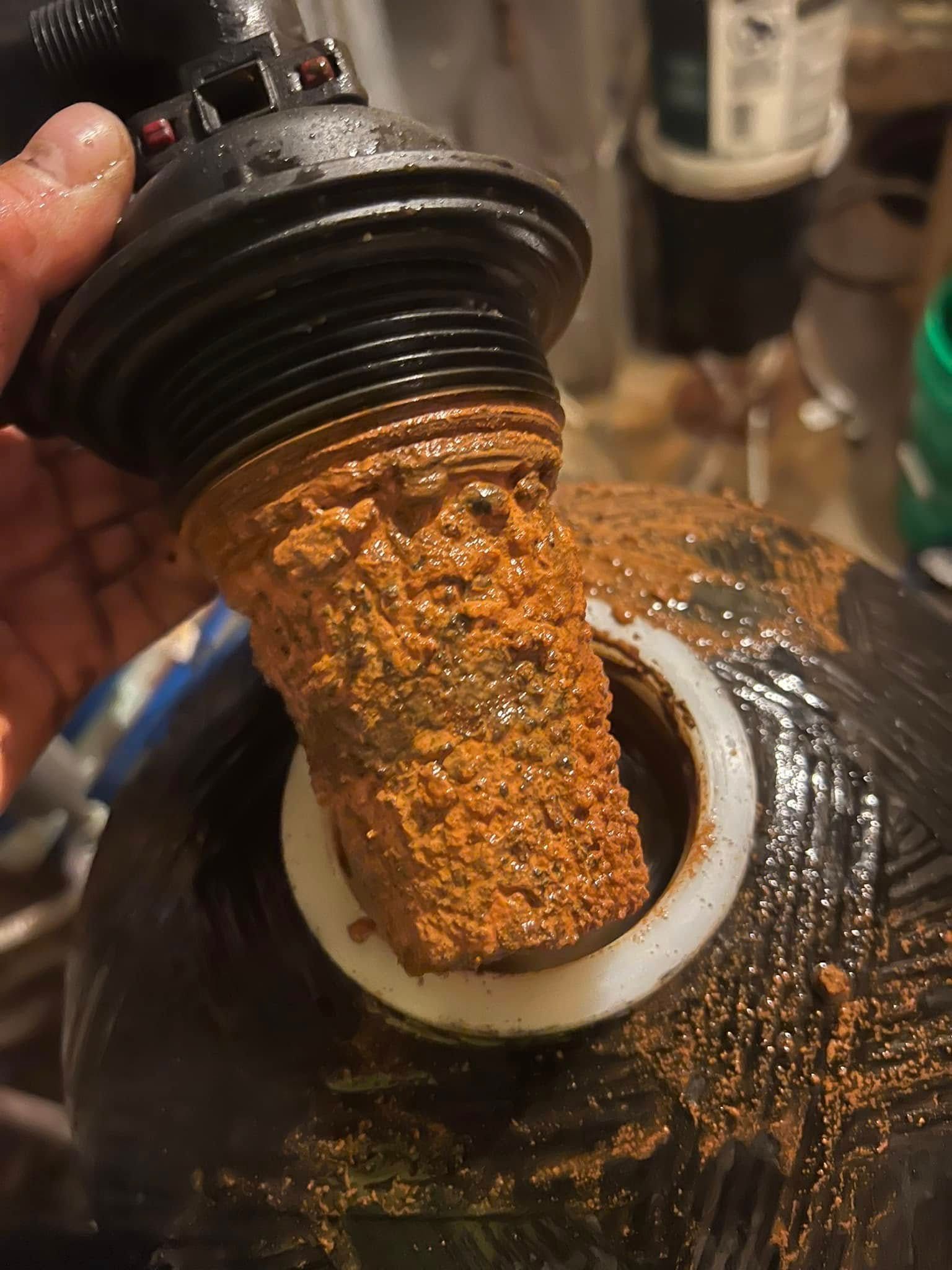 A person is holding a rusty pipe with a hole in it.