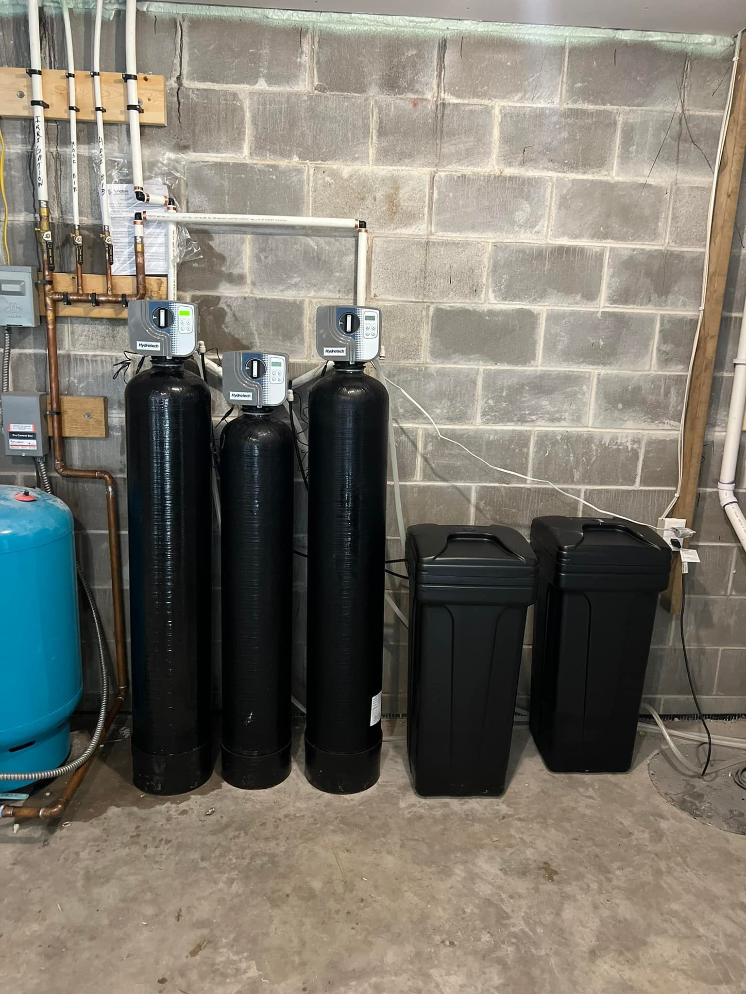 A row of black tanks sitting next to each other in a basement.