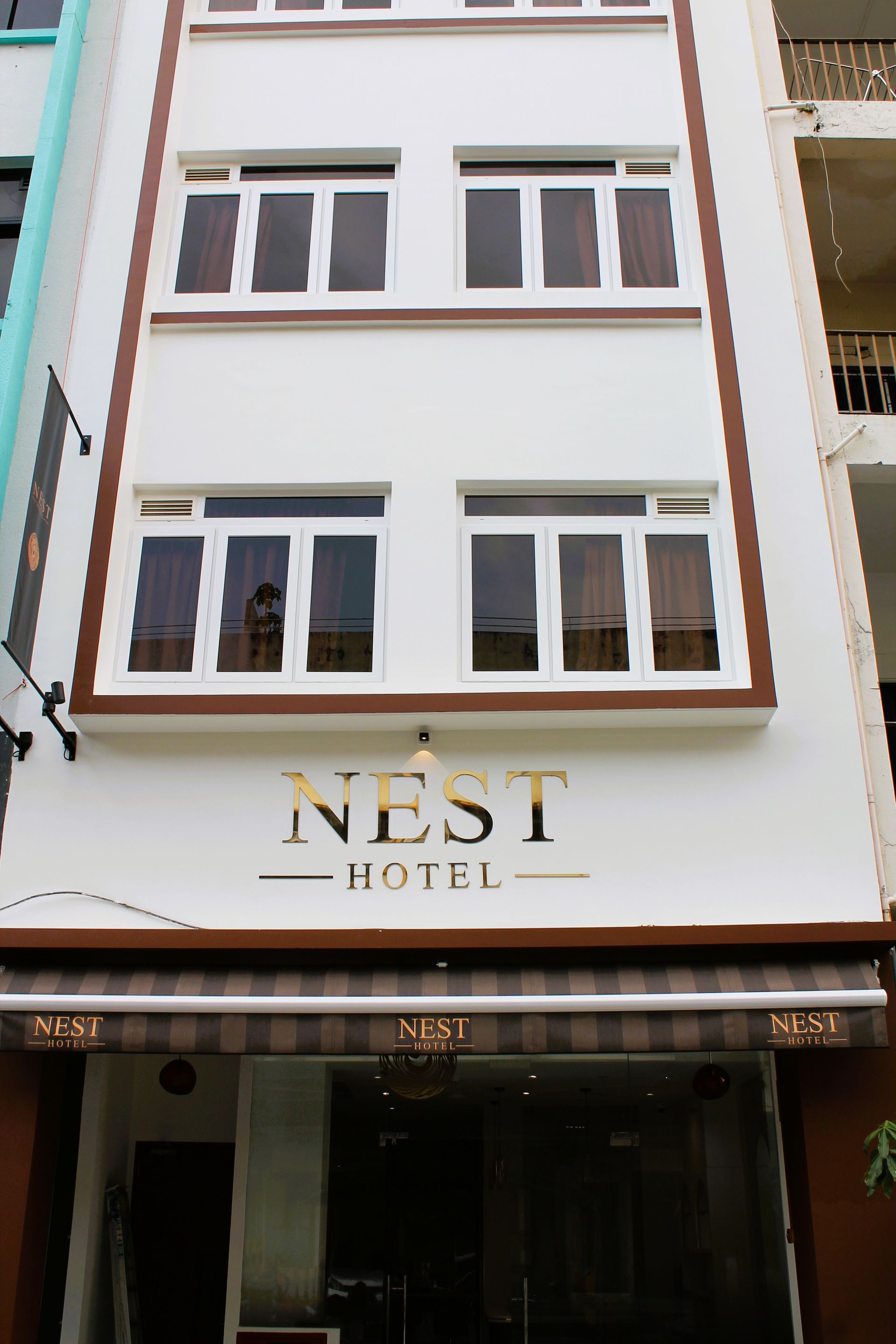 A white building with a sign that says nest hotel