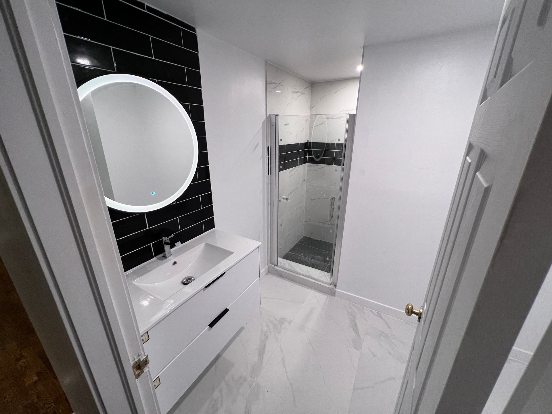 Une salle de bain avec lavabo, miroir et douche.