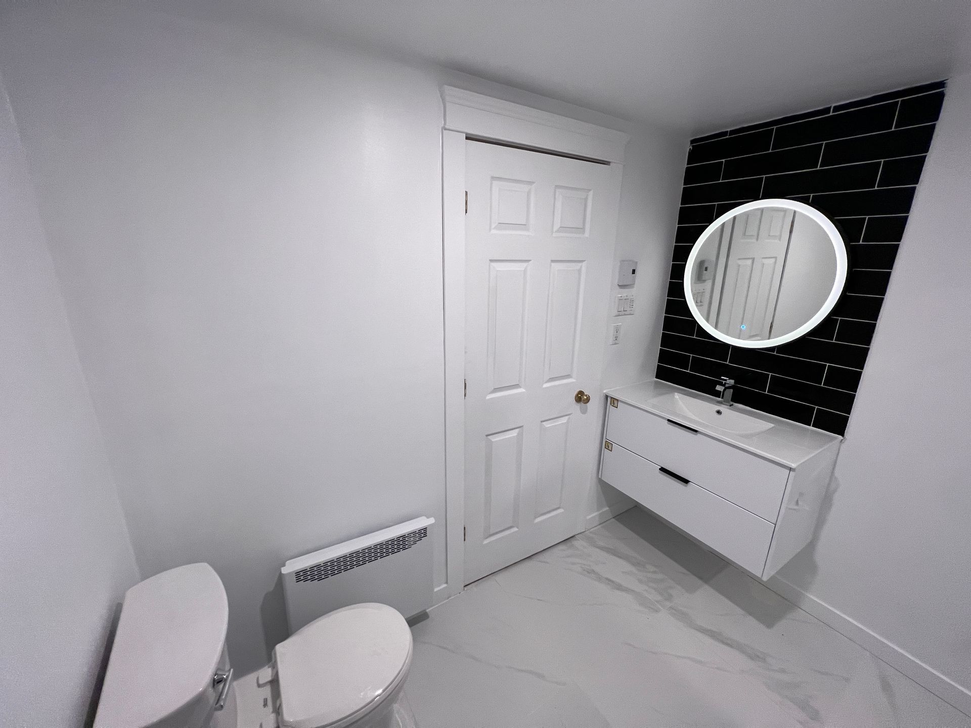 Une salle de bain avec WC, lavabo et miroir.