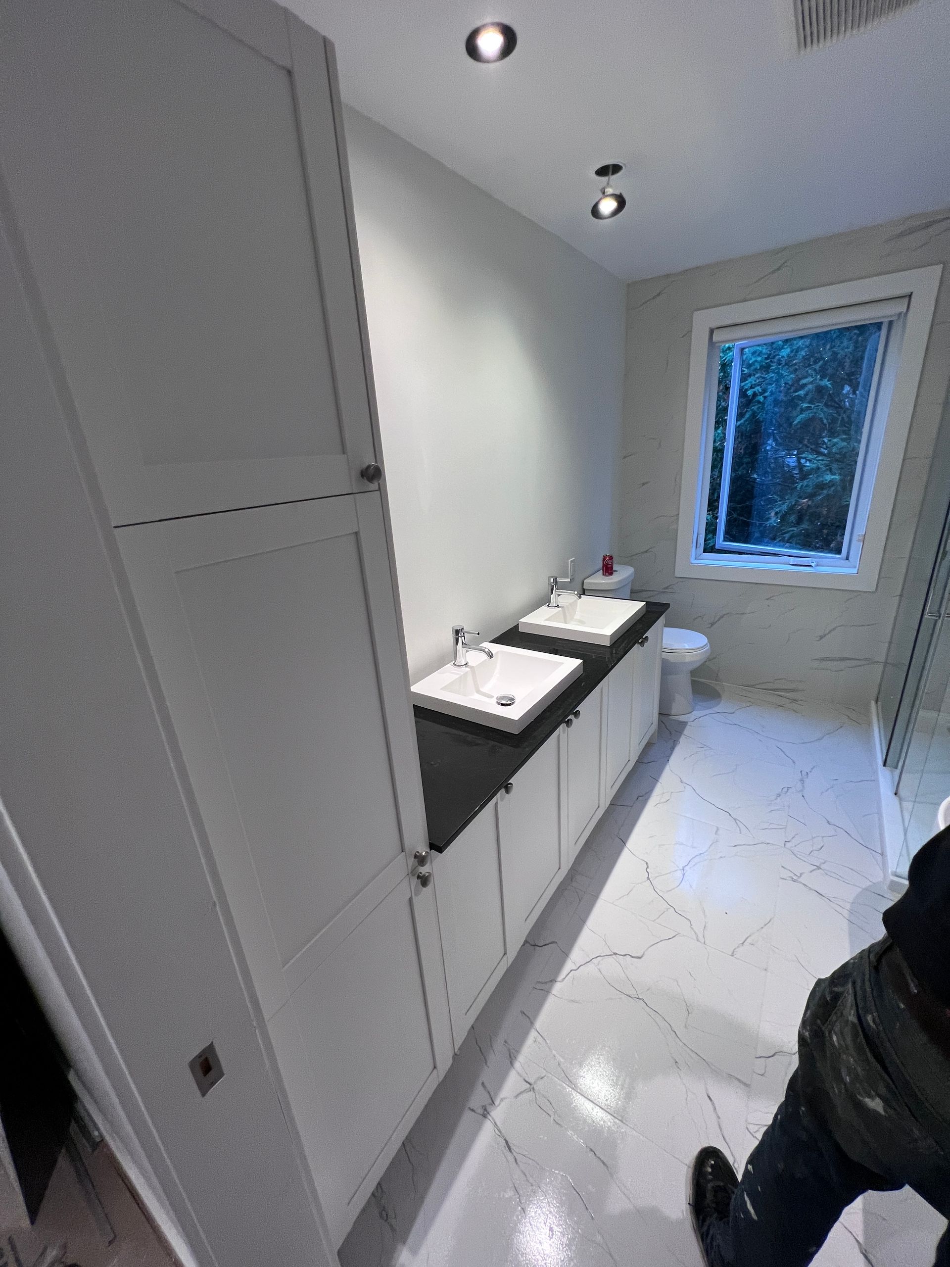 Une salle de bain avec deux lavabos, un WC et une fenêtre.