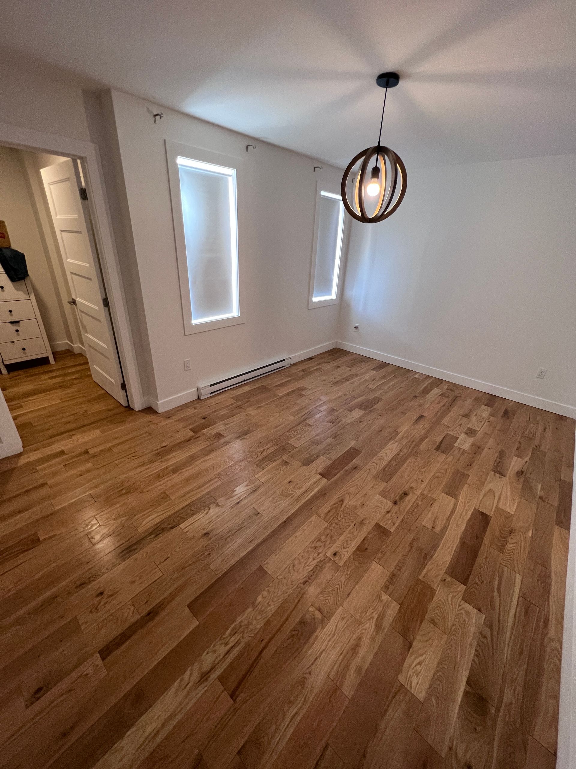 Une pièce vide avec du parquet et un lustre suspendu au plafond.