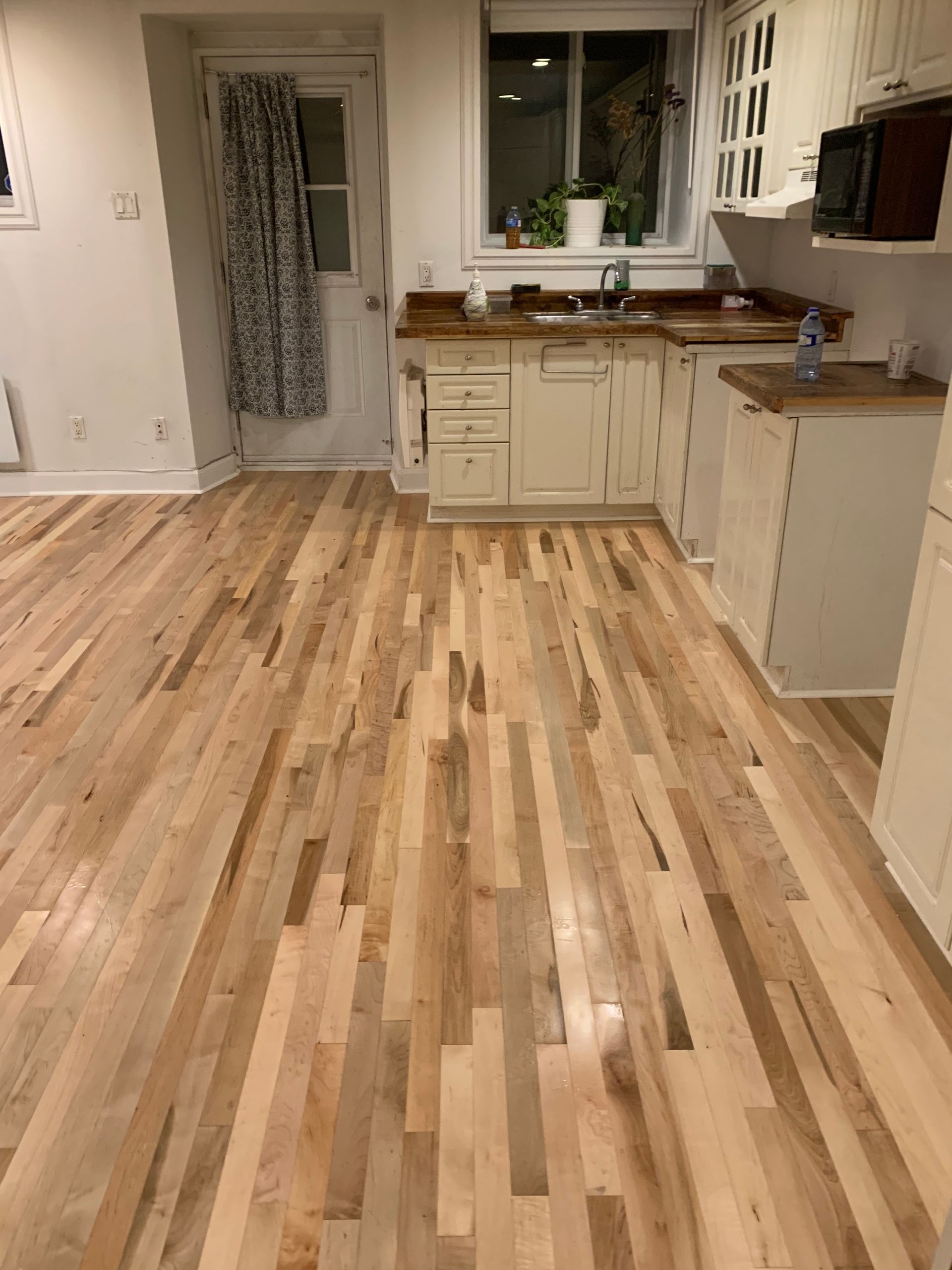 Une cuisine avec planchers de bois franc et armoires blanches.