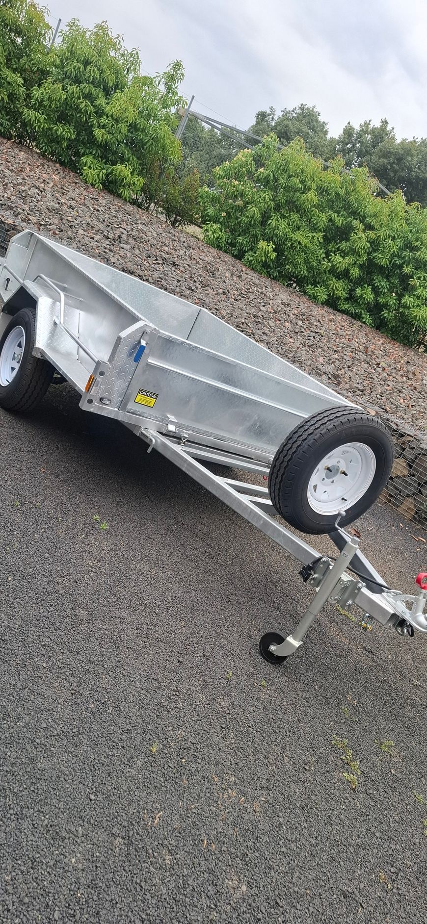 Silver Trailer With White Wheels is Parked on Gravel With Greenery in the Background — Towform Trailers in Brocklehurst, NSW