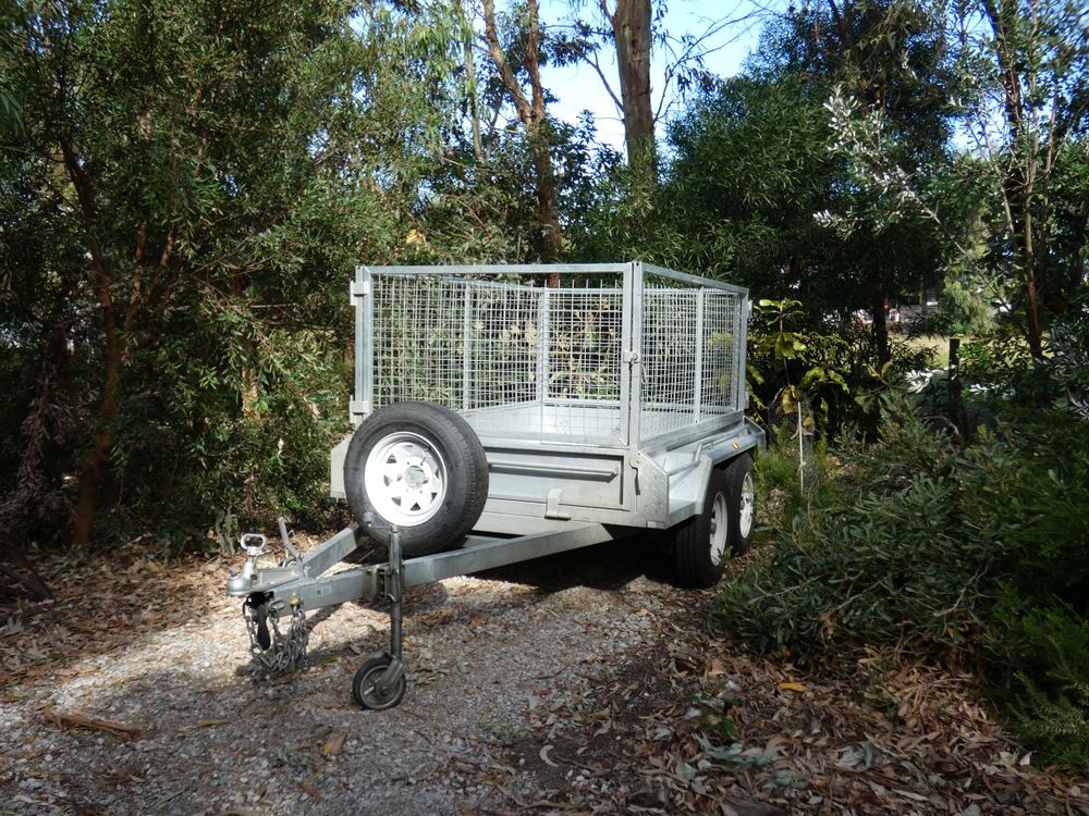 A Silver Trailer With a Caged Bed Sits on a Gravel Path — Towform Trailers in Brocklehurst, NSW