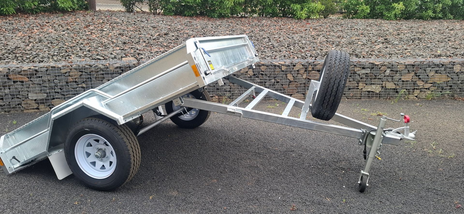 A silver utility trailer with a spare tire on a gravel surface — Towform Trailers in Brocklehurst, NSW