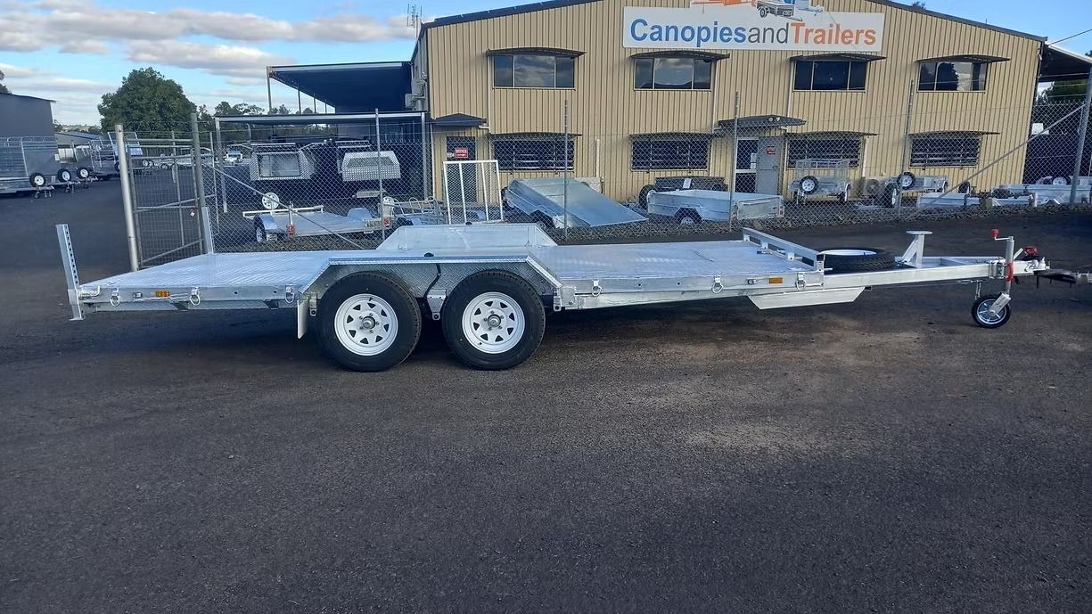 A Silver Car Trailer Parked On Asphalt In Front Of A Building — Towform Trailers in Parkes, NSW