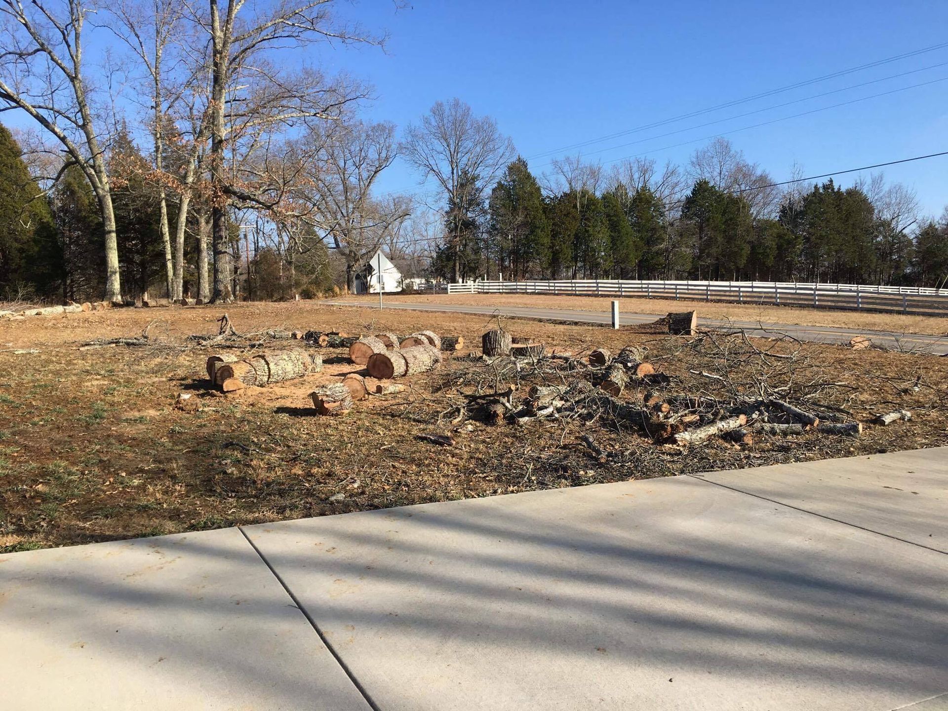 Remains of brick foundation in a grassy field, trees in the background, with a clear blue sky.