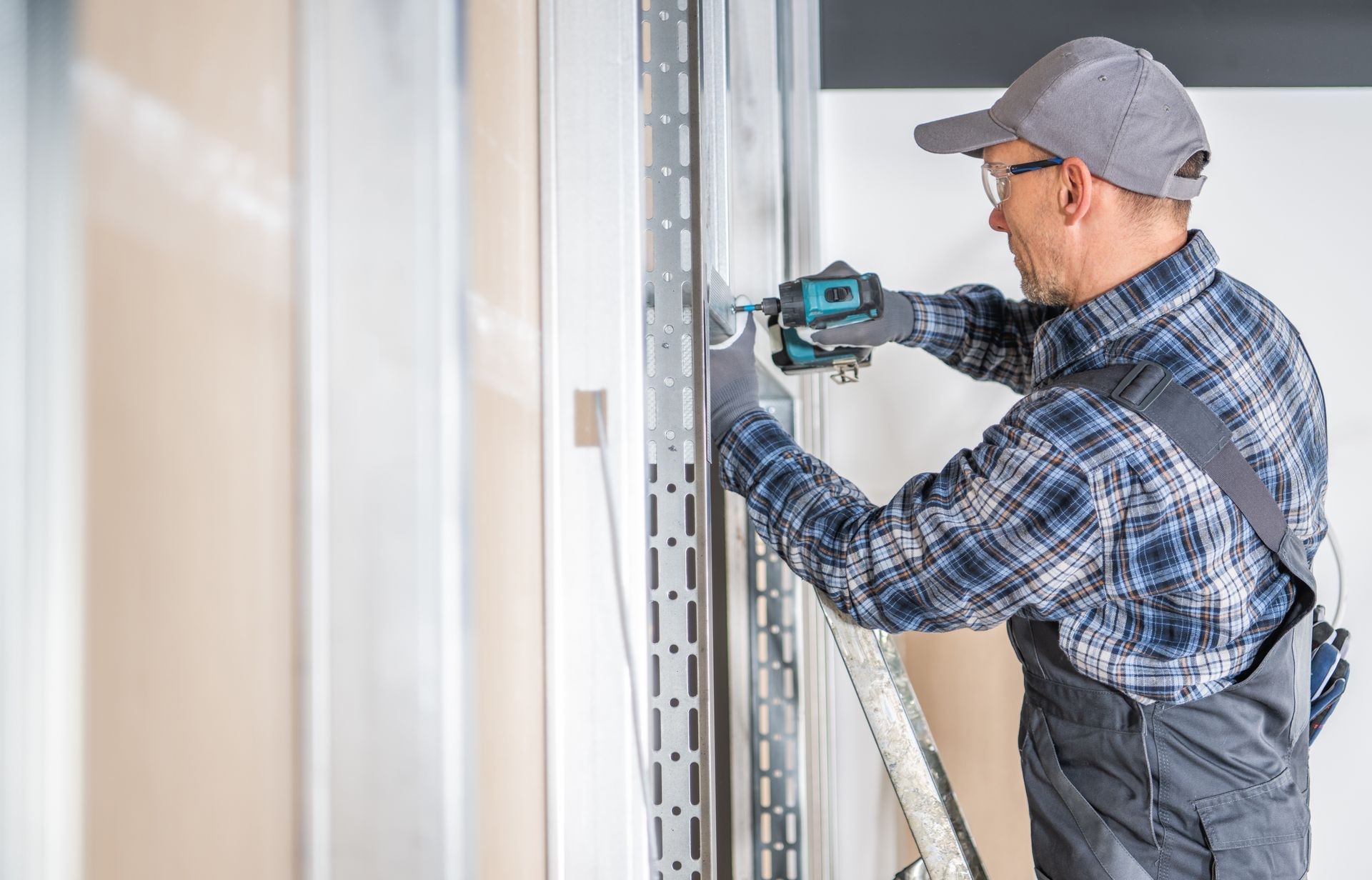 A man is working on a wall with a drill.