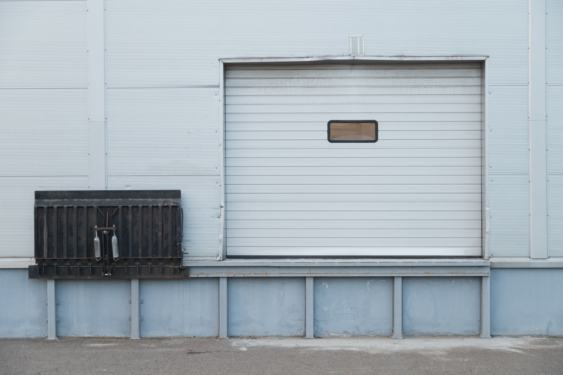 A white warehouse door with a ramp attached to it.